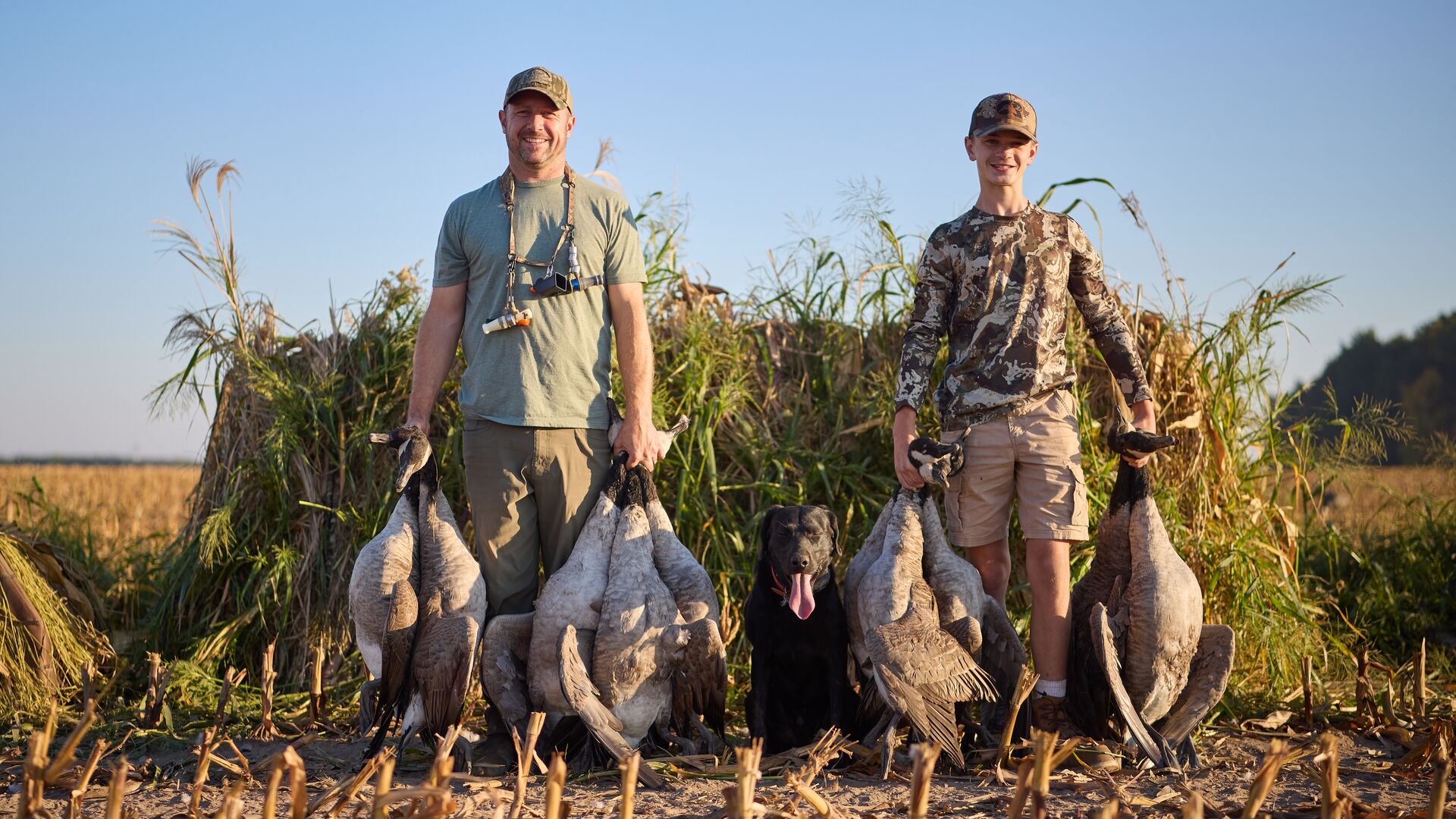 Man and boy with geese after hunt, youth hunting license concept.