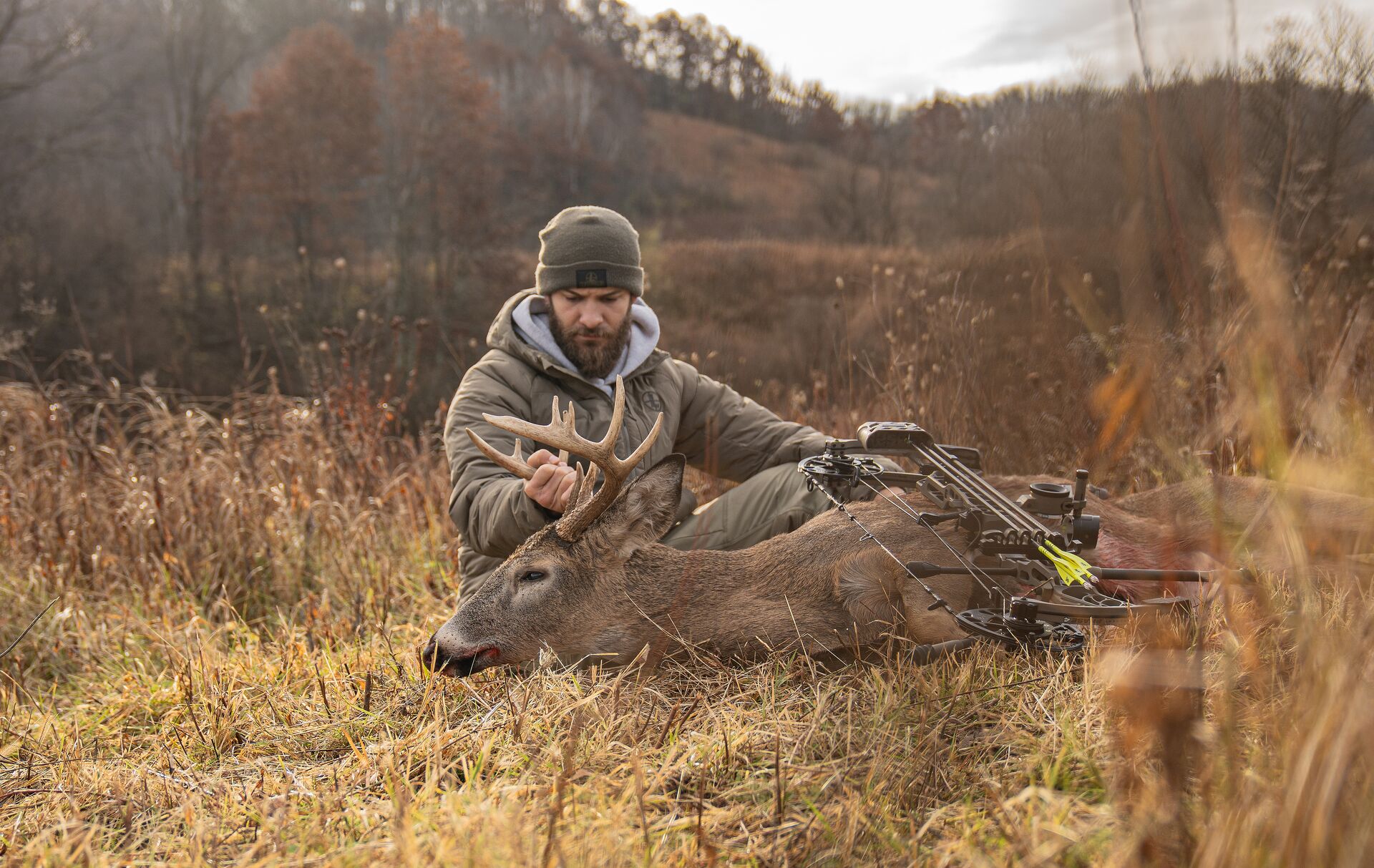 Hunter sits with bow and buck deer after hunt, get a Texas hunting license concept.