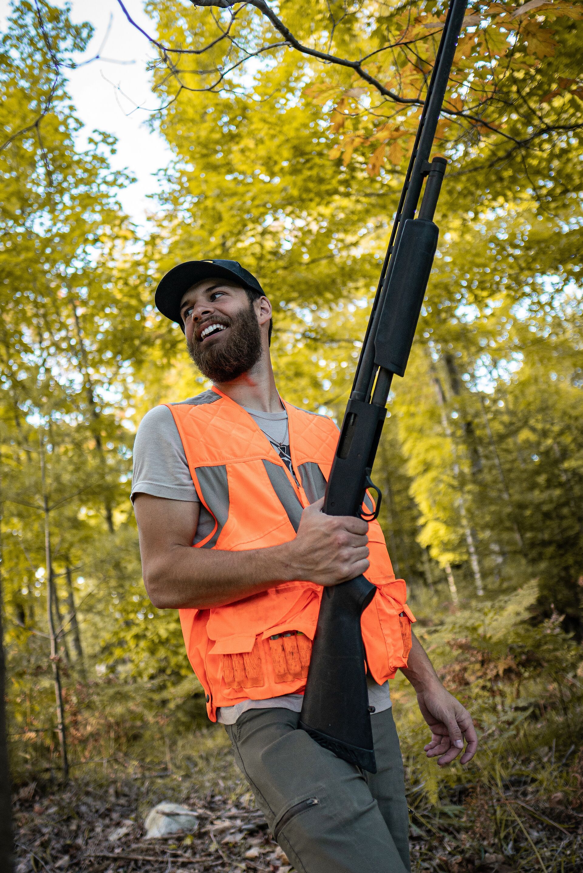 Hunter in blaze orange smiling with firearm, hunter education field day concept.
