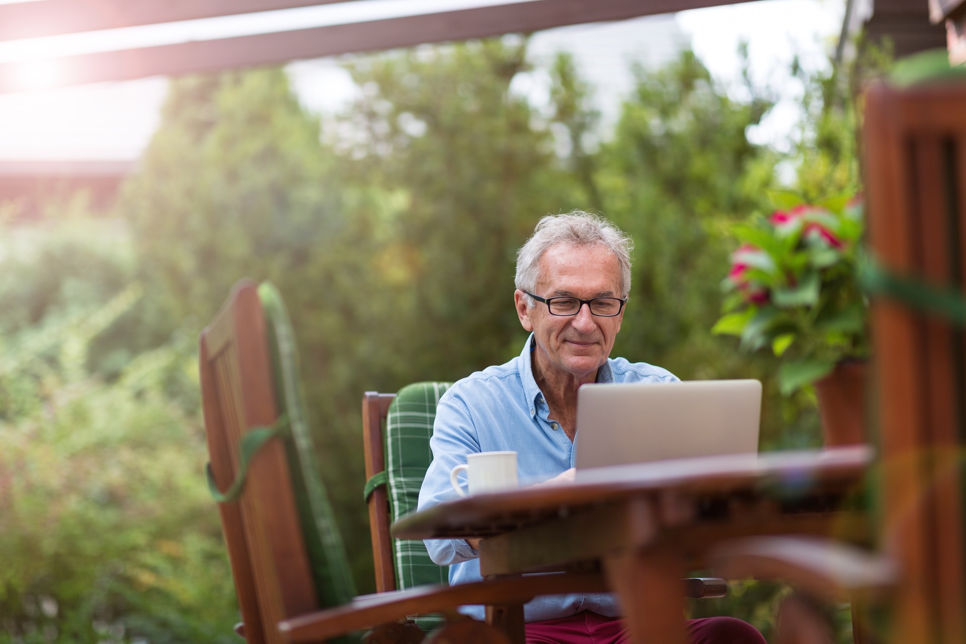 Man sits at table to use laptop, online vs in-person hunter education concept. 