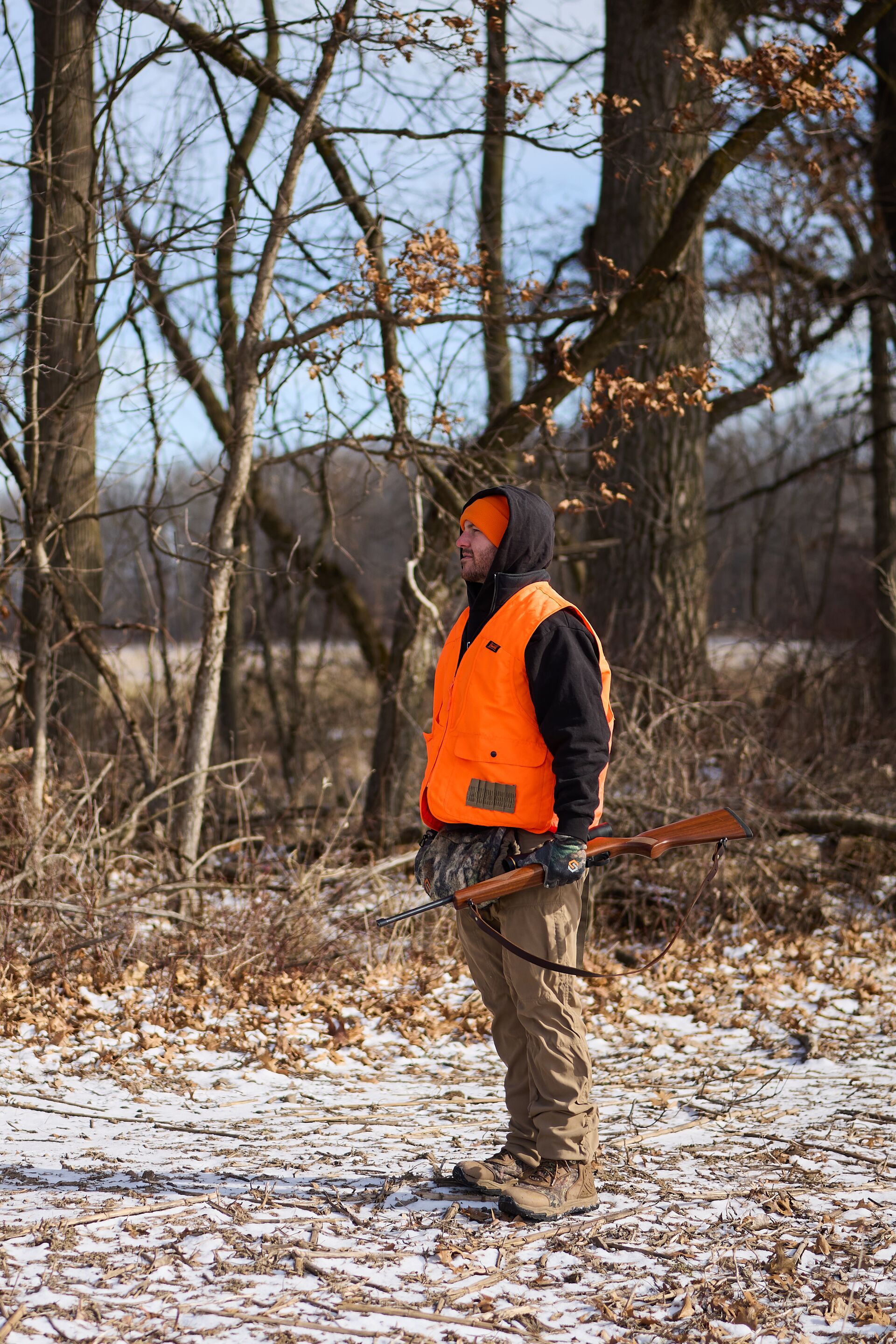 Hunter in blaze orange vest with firearm, turkey hunting safety tips concept. 