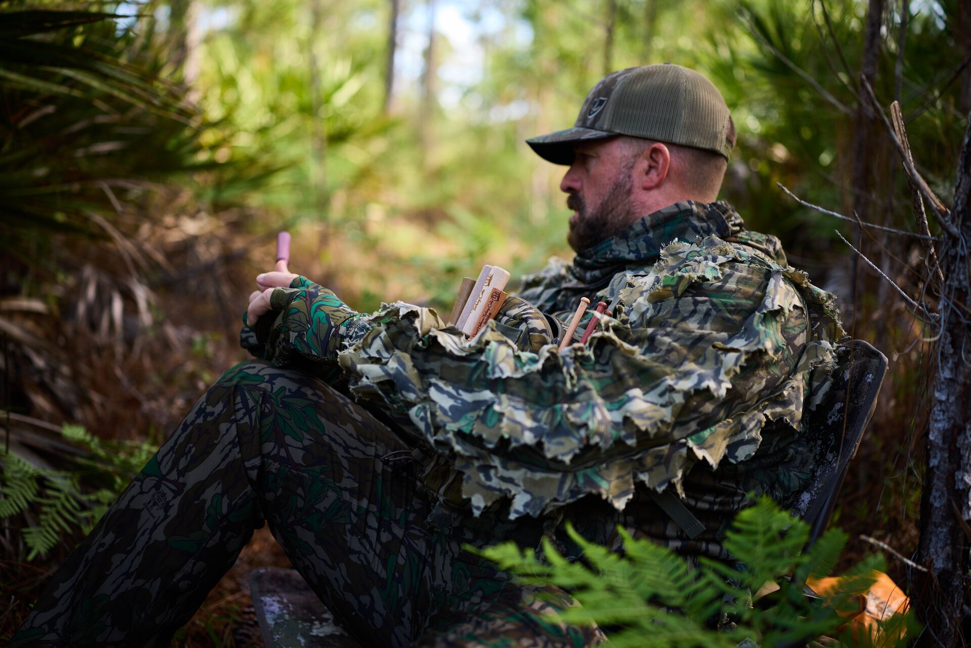 Hunter in camo uses turkey call in the woods. 