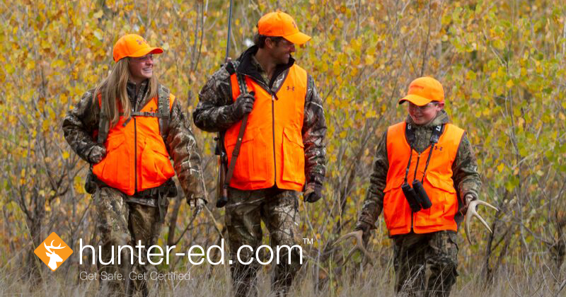 Three hunters in blaze orange, taking an online hunter education course concept.